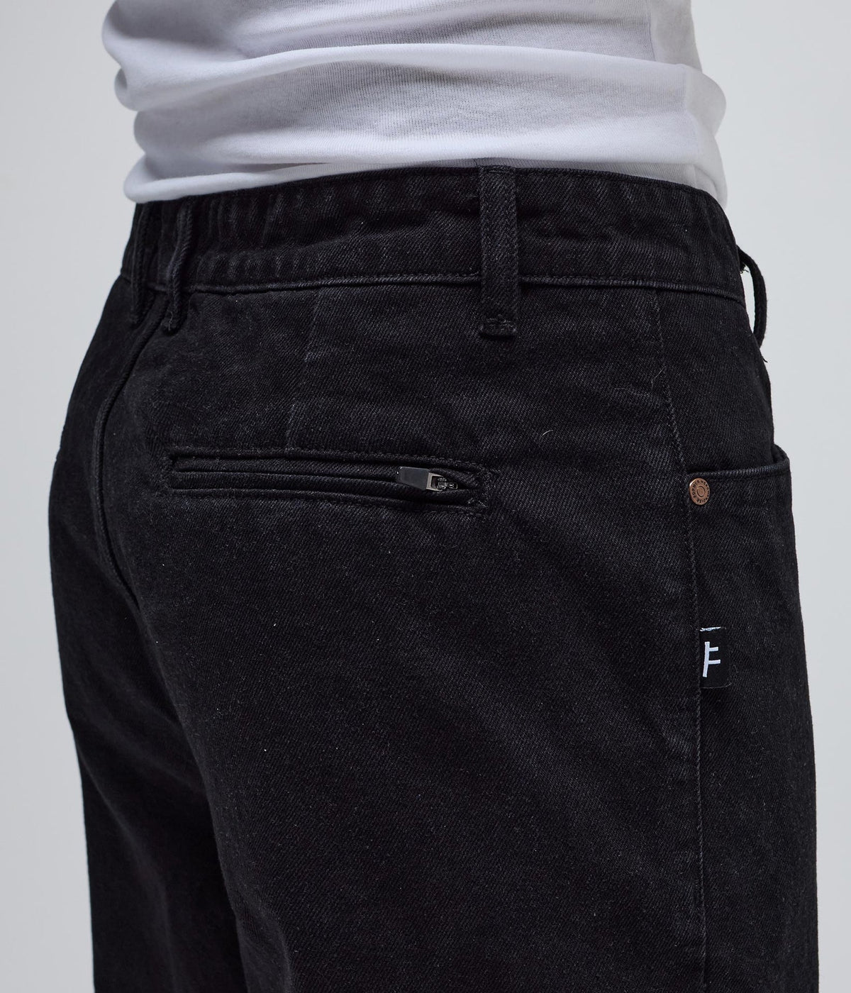 Black denim pants by FORMER AG, showing slim fit style with classic five-pocket design and belt loops.
