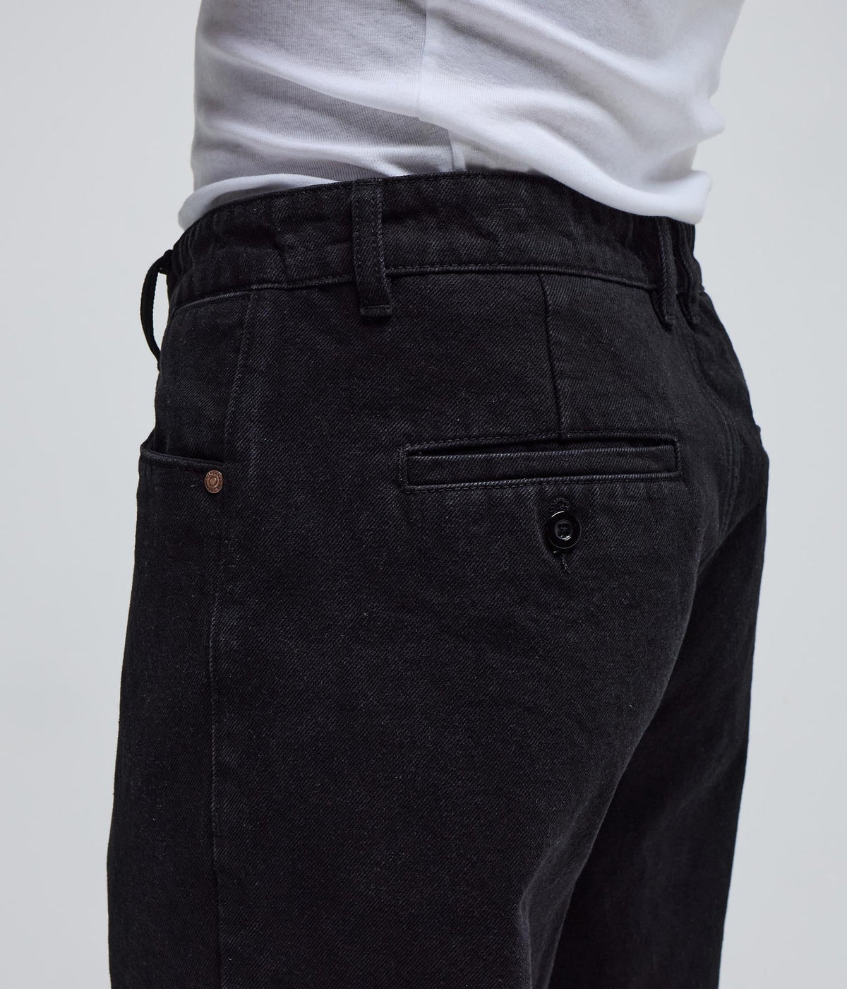 Black denim pants by FORMER AG, shown on model with relaxed fit and classic five-pocket design.