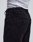 Black denim pants by FORMER AG, shown on model with relaxed fit and classic five-pocket design.
